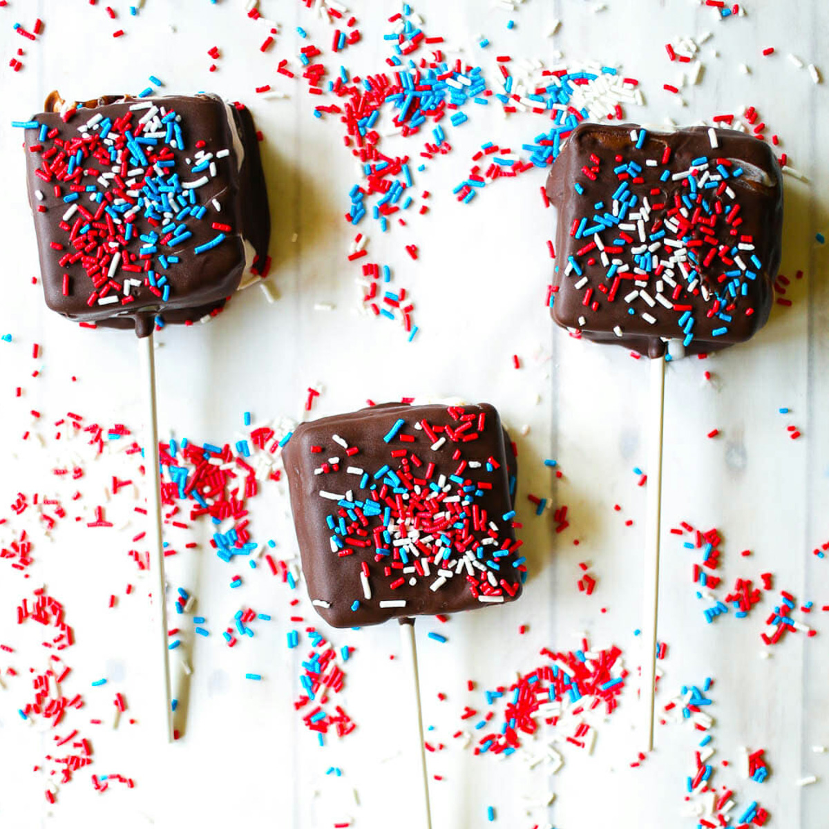 chocolate covered ice cream sandwiches on sticks with sprinkles