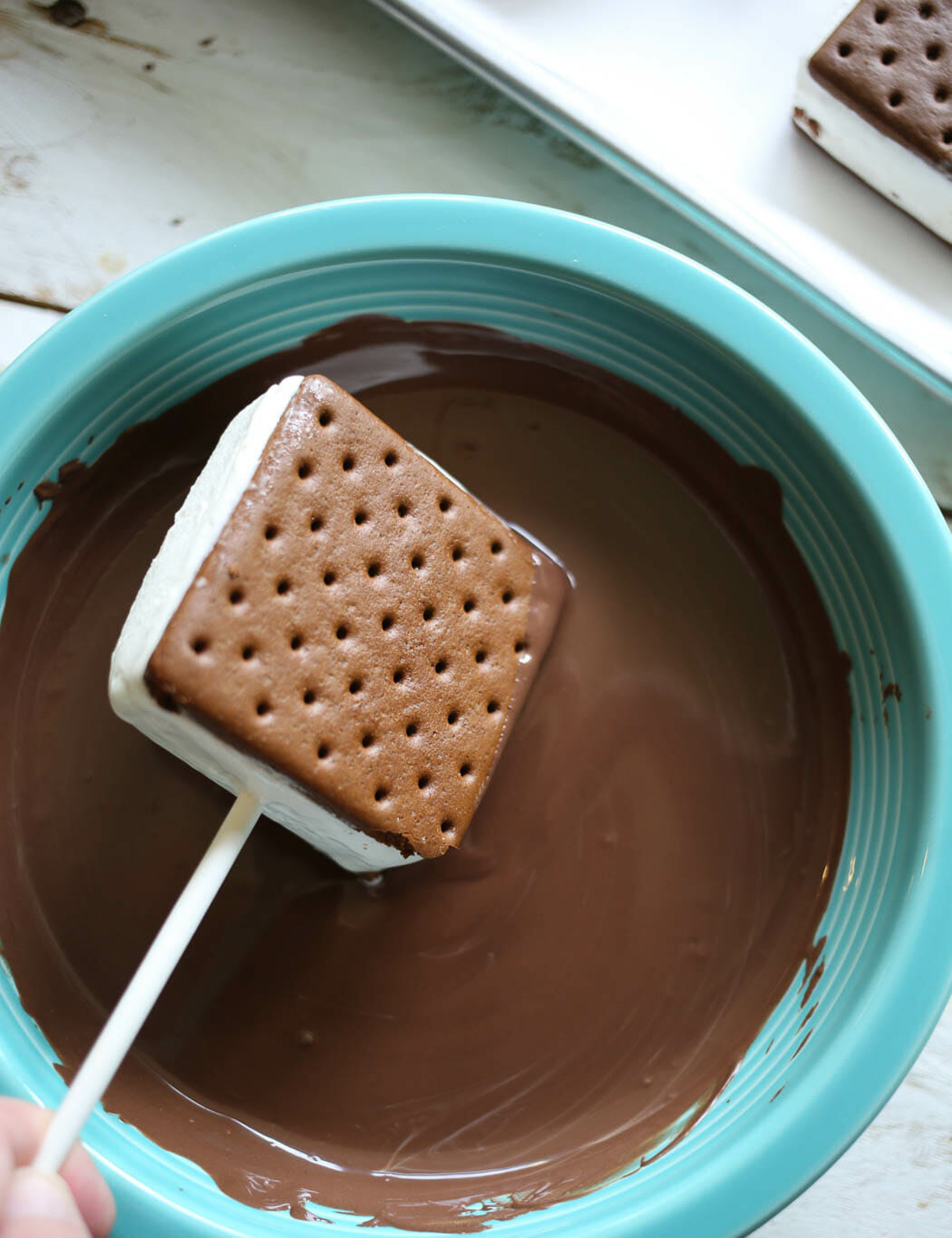 dipping an ice cream sandwich in melted chocolate