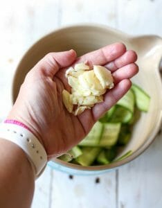 Adding garlic to cucumber ribbons for quick pickles from Our Best Bites