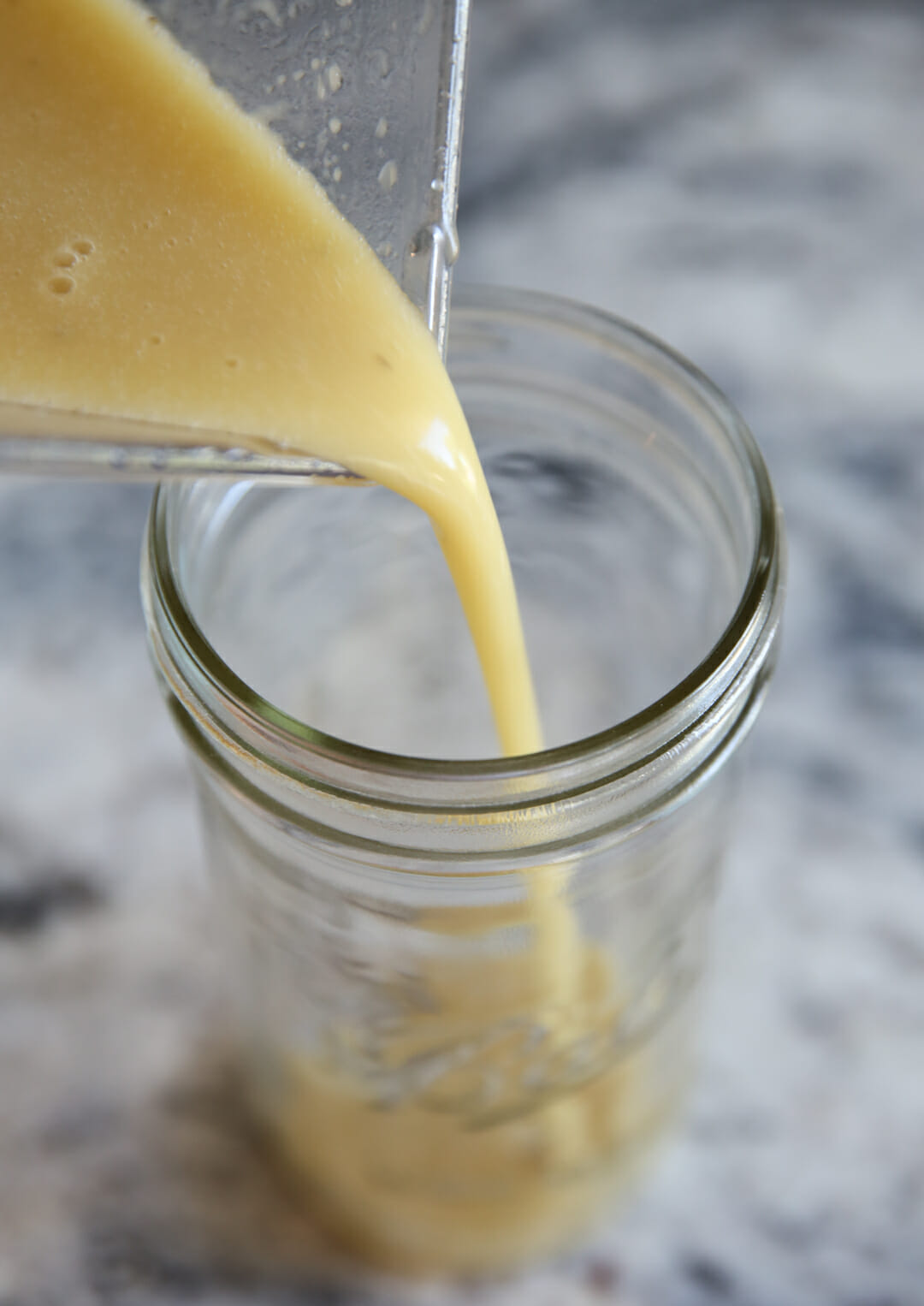 pouring honey cider dressing into mason jar