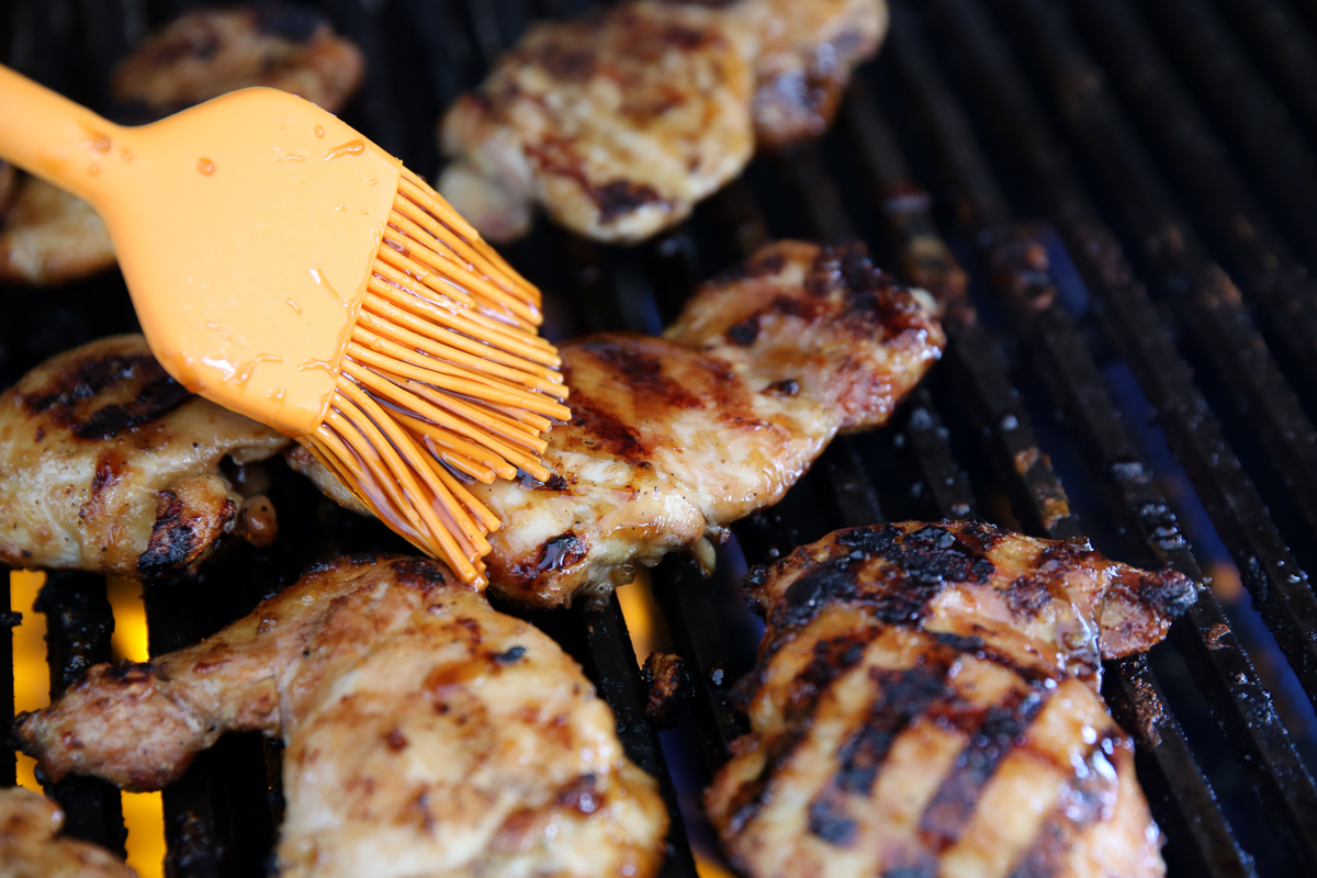 grilled chicken being glazed with Teriyaki Sauce