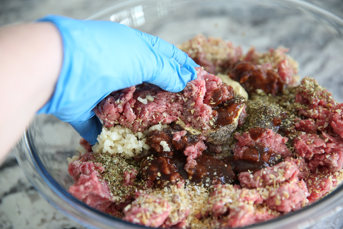 hand mixing raw beef with seasonings