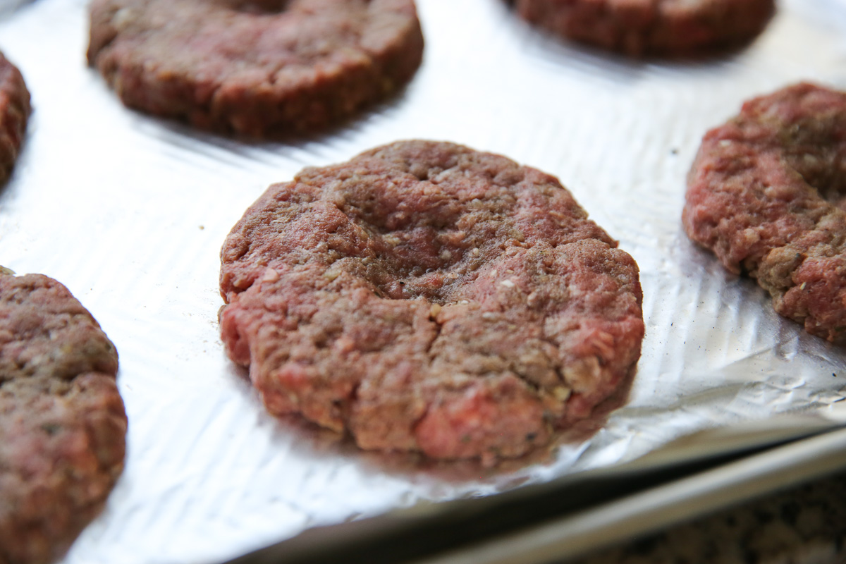 raw burgers shaped into patties with indentations on top