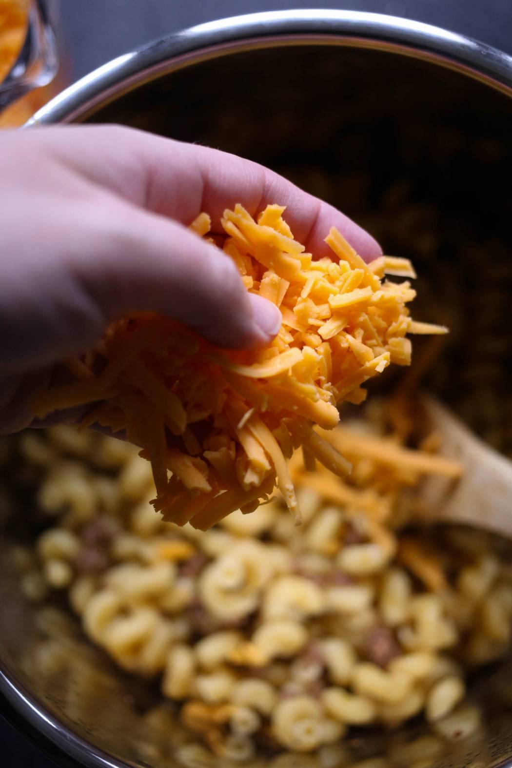 adding shredded cheese to instant pot cheeseburger macaroni from our best bites