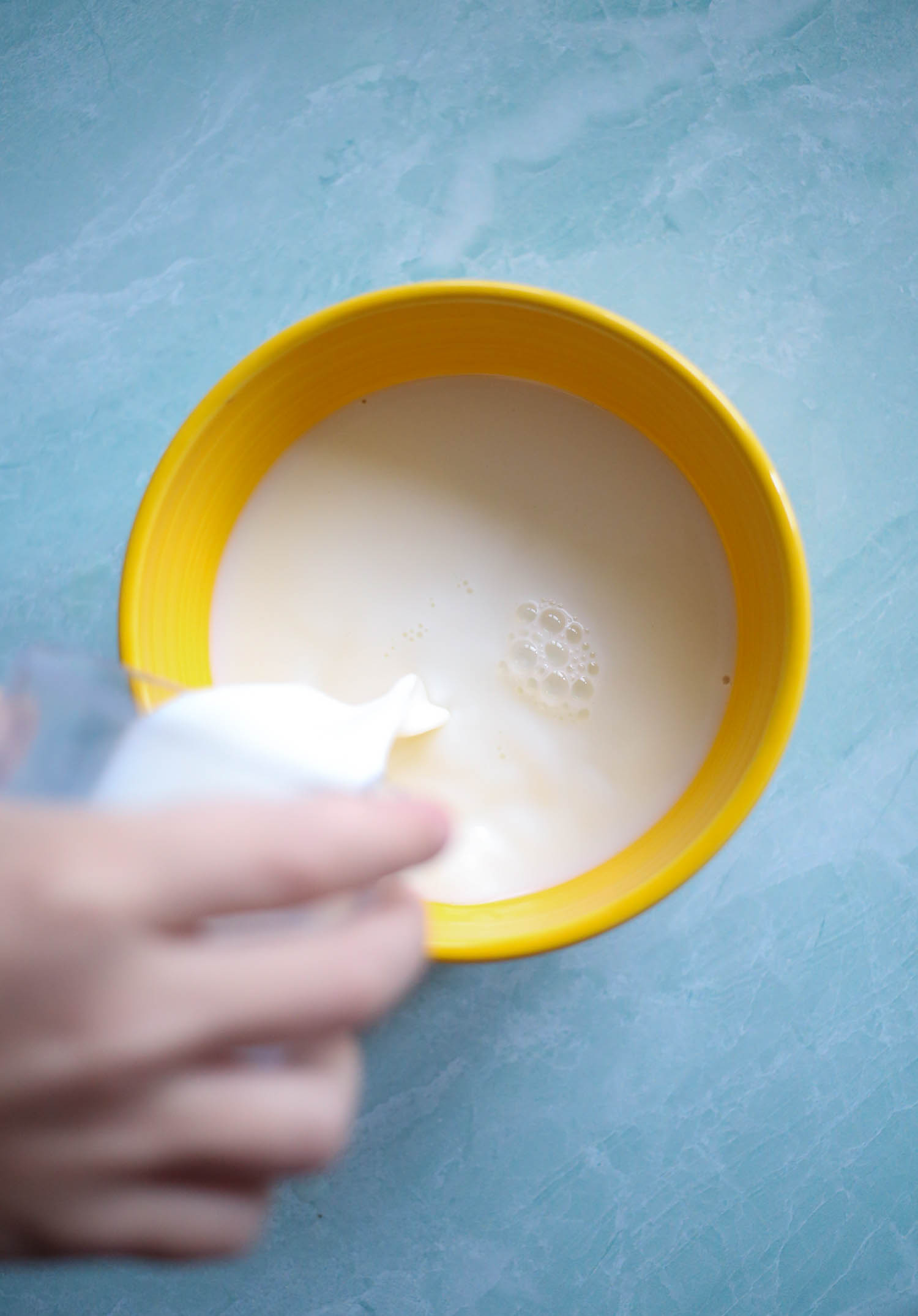adding milk to bowl for mixed berry baked oatmeal from our best bites