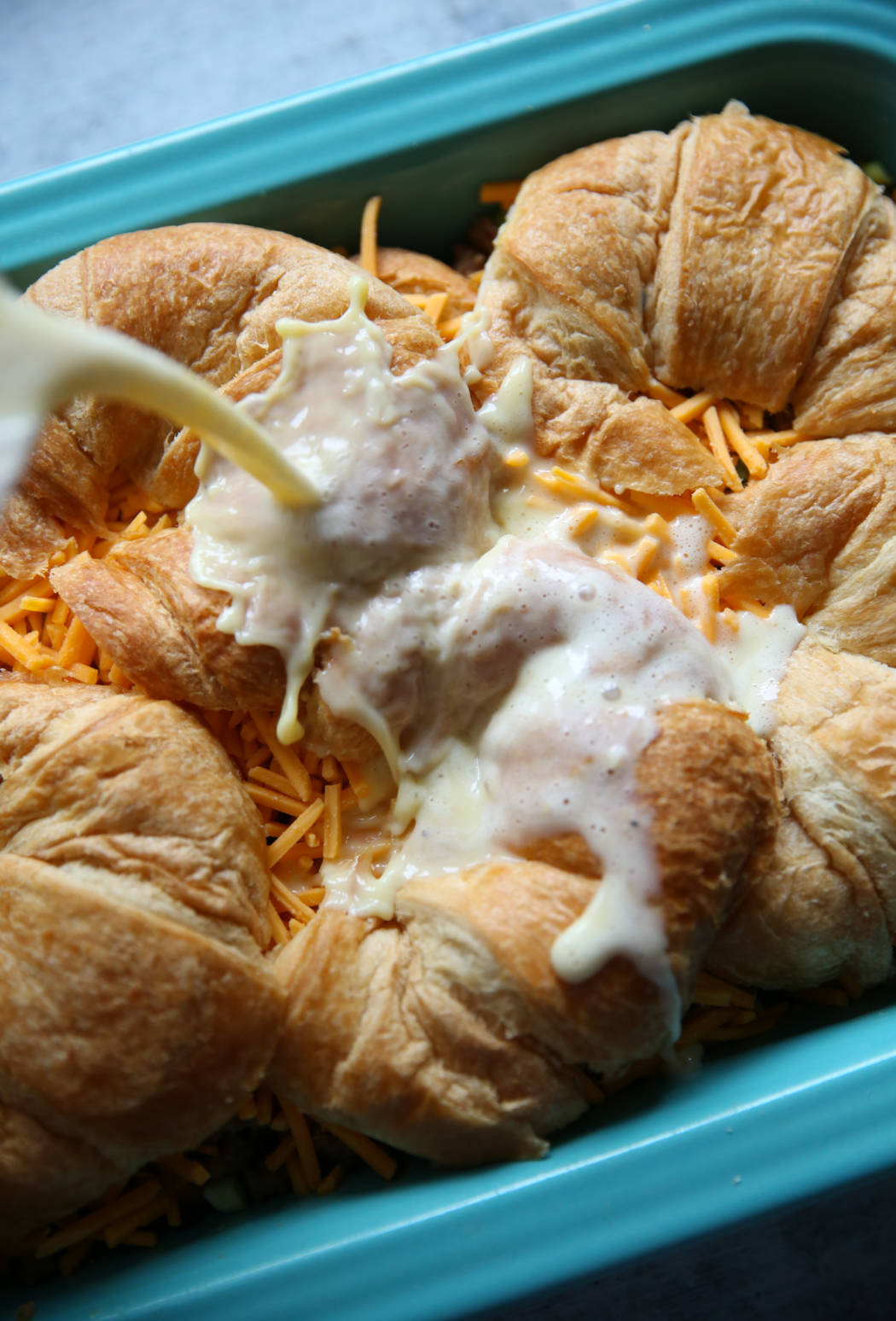 pouring egg and milk mixture over croissants