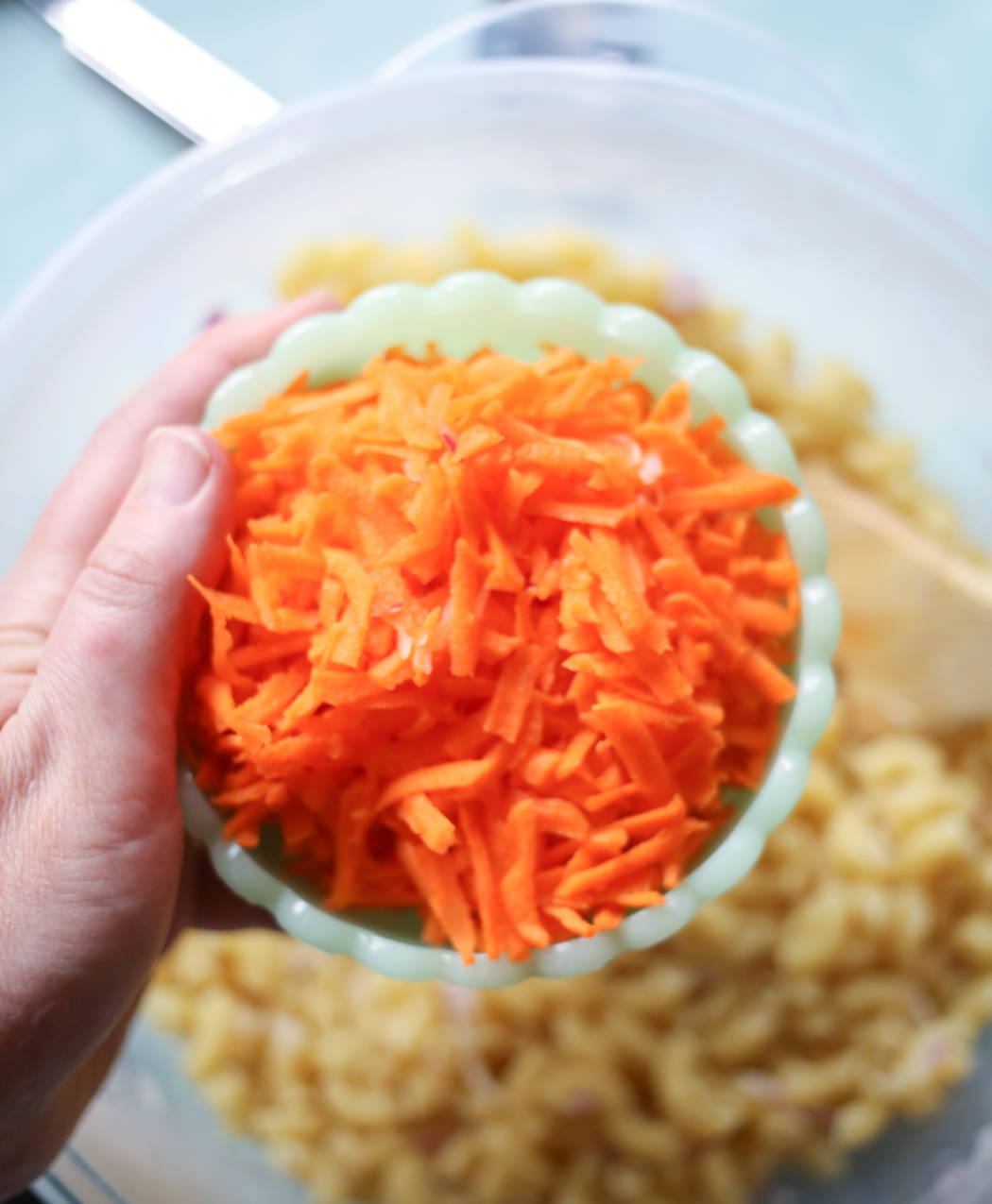 adding shredded carrots to macaroni salad