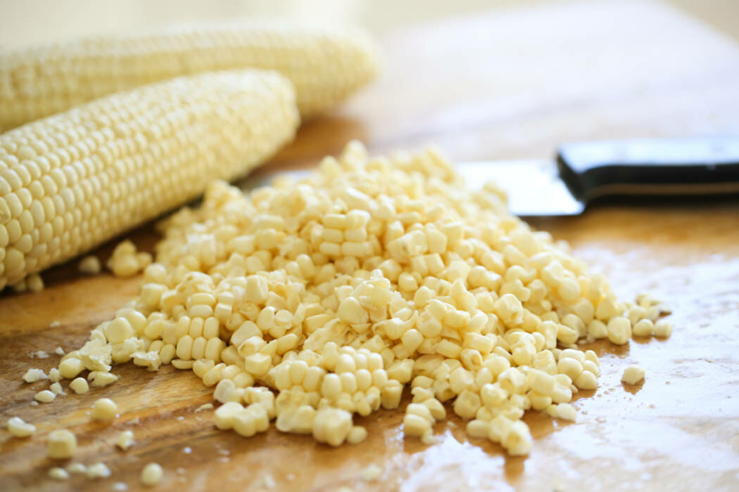 Corn trimmed from the cob on a cutting board. 