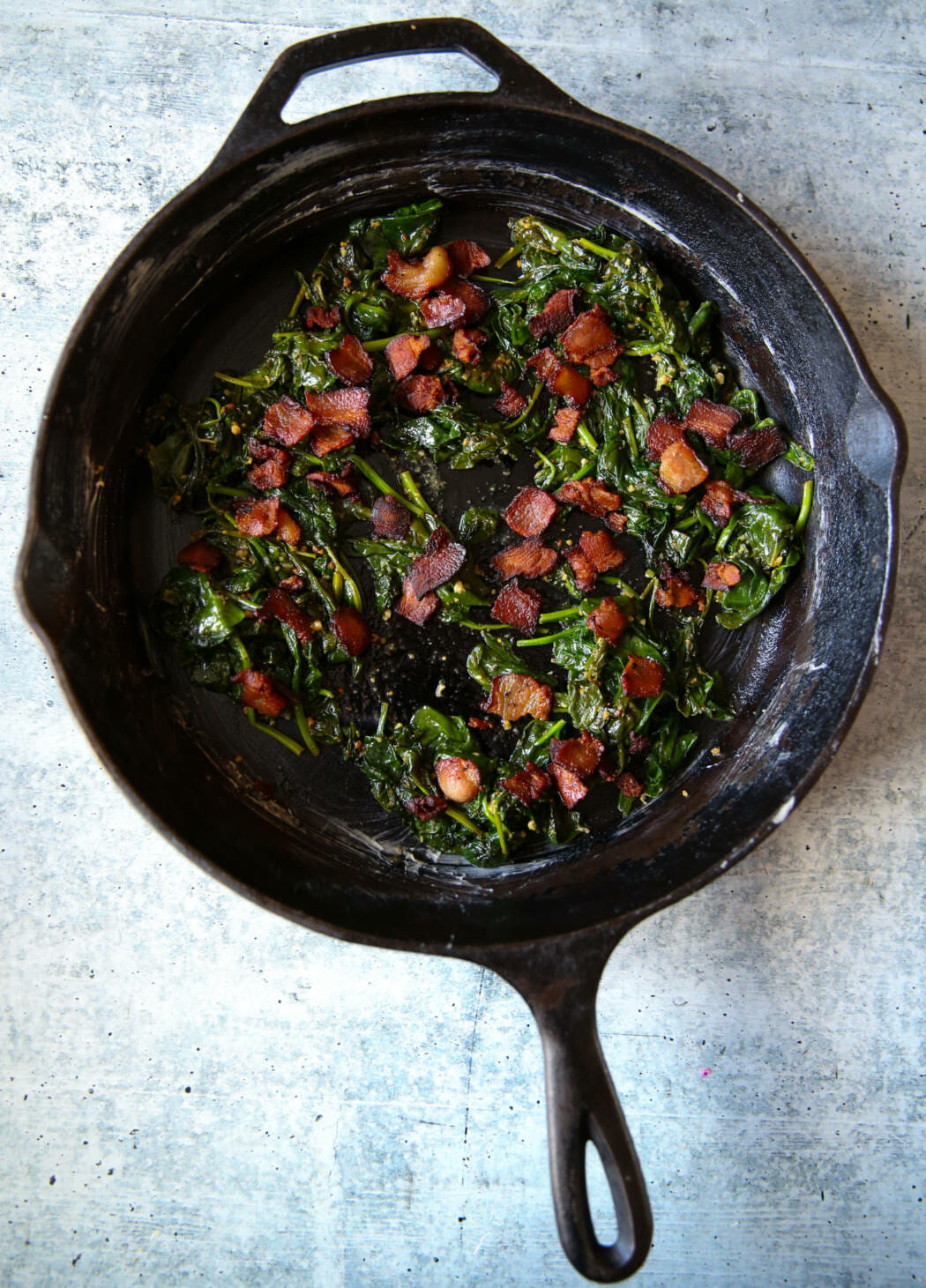 bacon and spinach in a cast iron pan