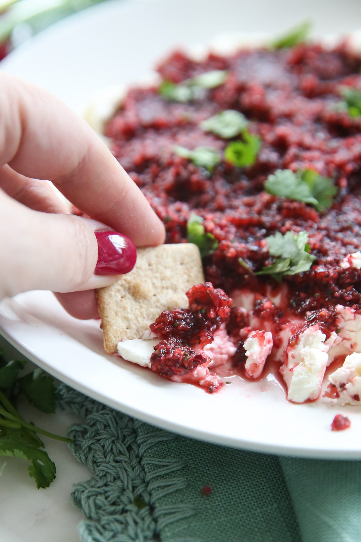 hand scooping cranberry salsa onto cracker