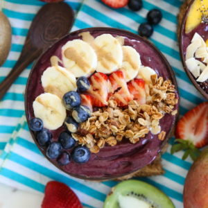 Acai smoothie in a bowl, topped with bananas, strawberries, blueberries, and granola