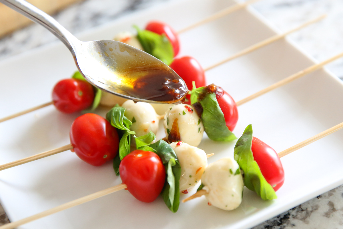 balsamic dressing drizzling over tomatoes and cheese
