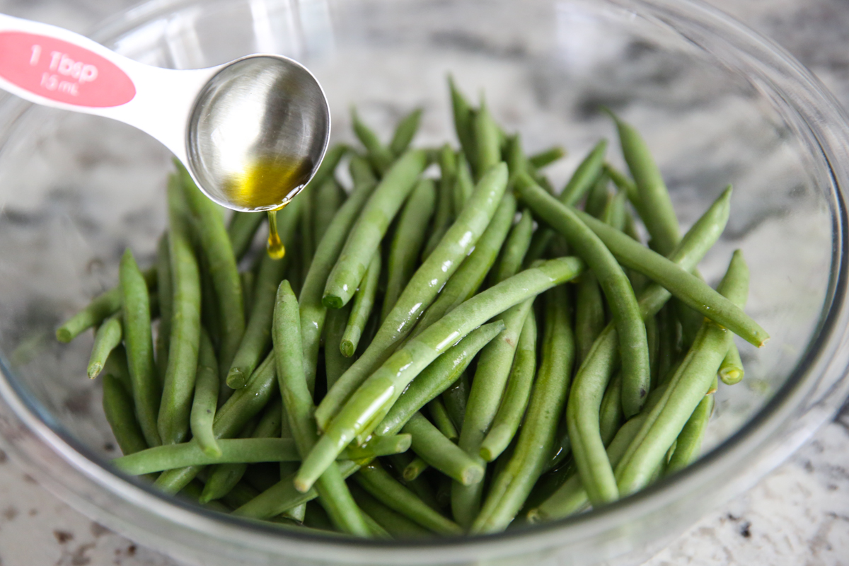 drizzling olive oil on green beans