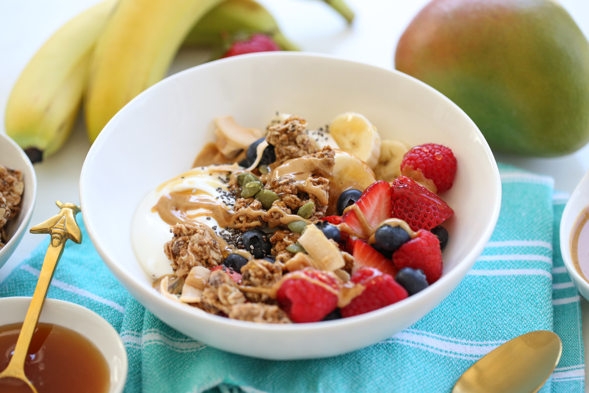 yogurt, granola, and fruit in a white bowl