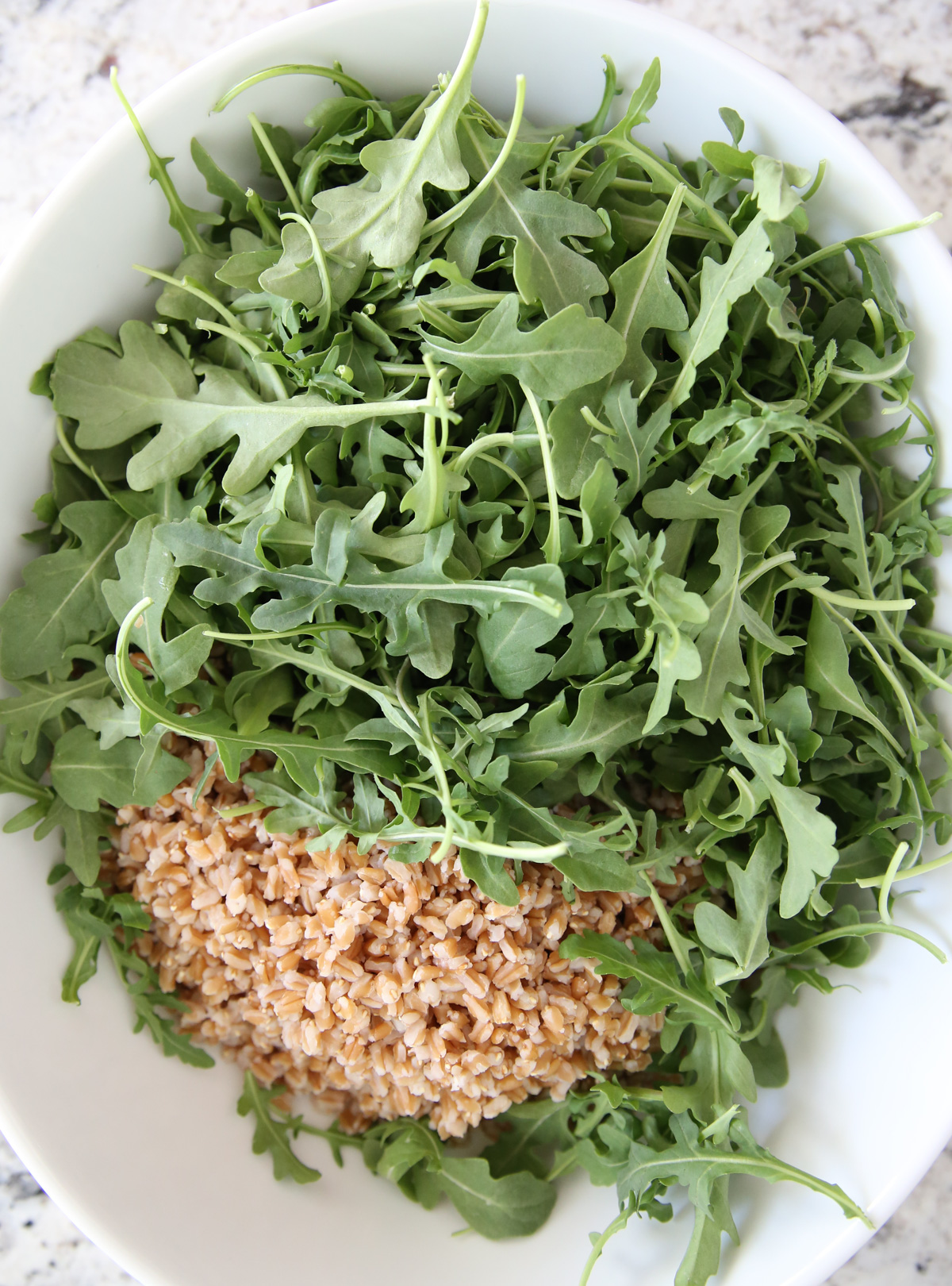 Cooked farrow and arugula in a serving bowl