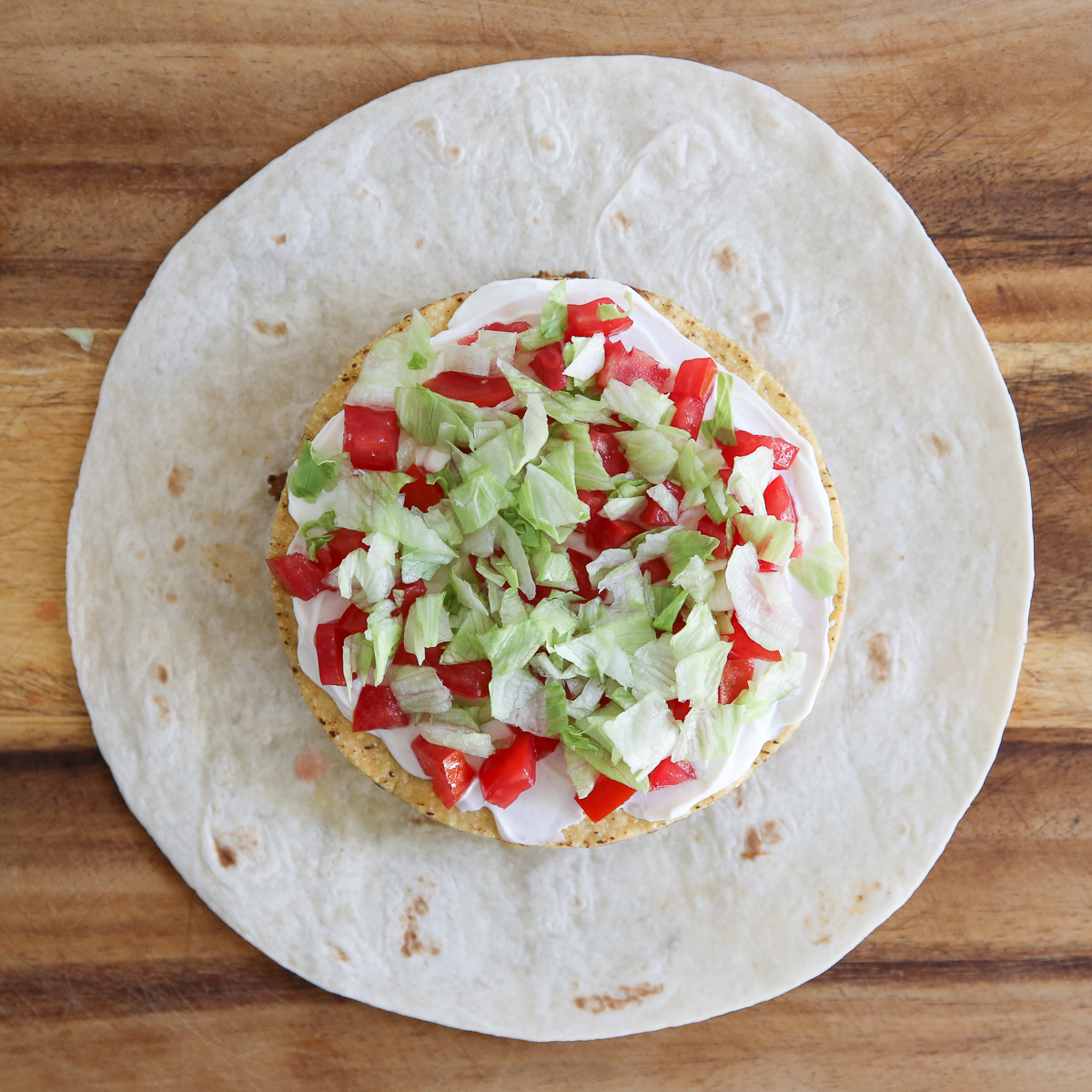 lettuce and diced tomatoes on a crunch wrap supreme