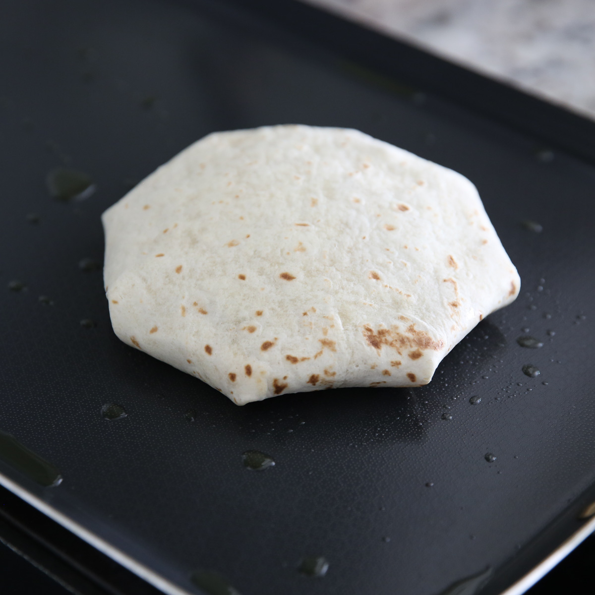 cooking a crunch wrap on a skillet