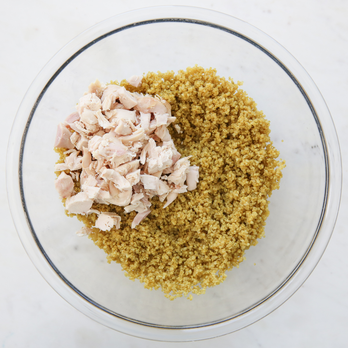 Cooked quinoa and chicken in a glass bowl
