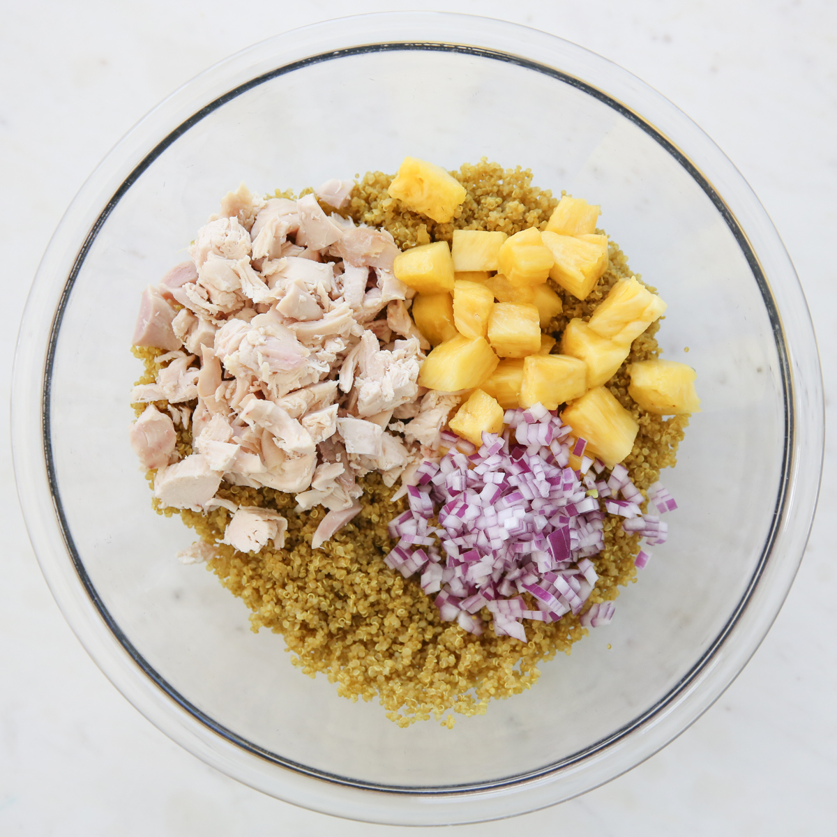 Cooked quinoa in a glass bowl and red onion