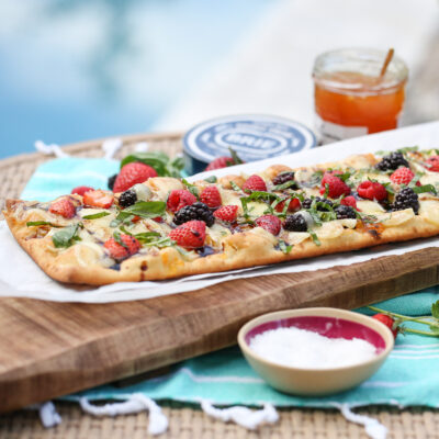 flatbread with fresh berries, brie cheese and condiments on a beautiful garden table
