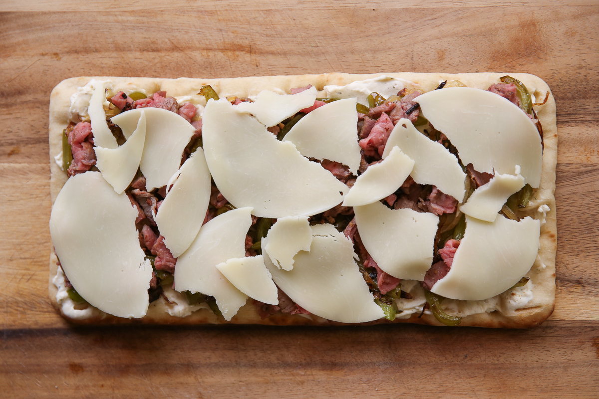 Cheesesteak flatbread on a cutting board