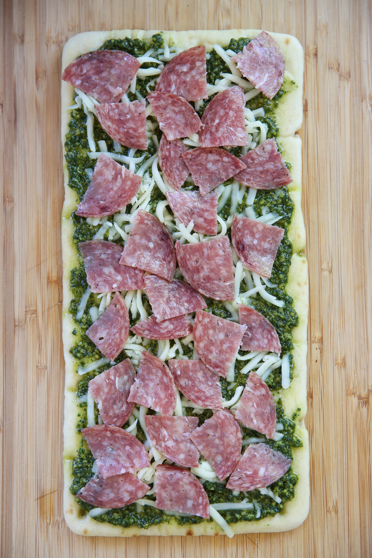 flatbread spread with pesto and cheese and salami