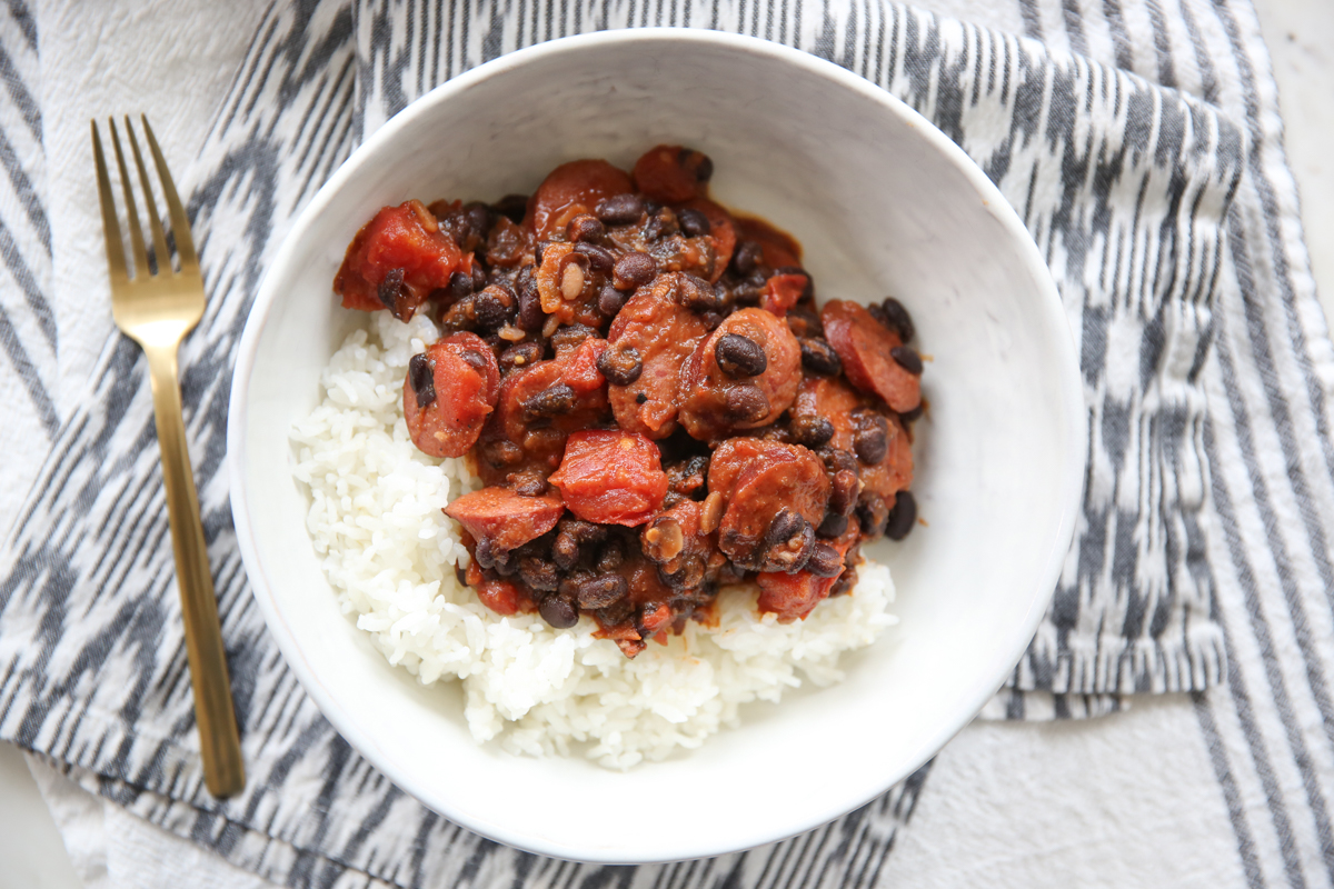 black bean kielbasa and tomatoes over rice in a white bowl