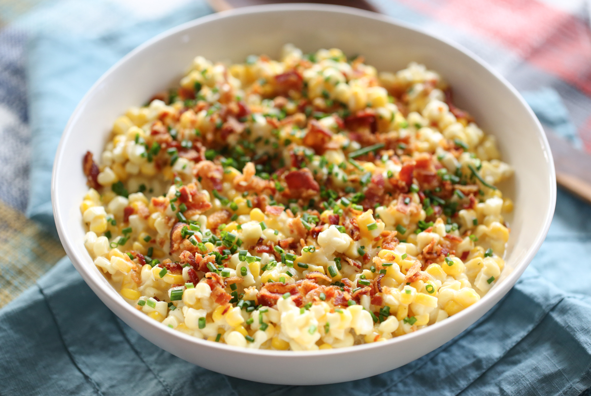 white bowl on a set table with crumbled bacon and chives on top