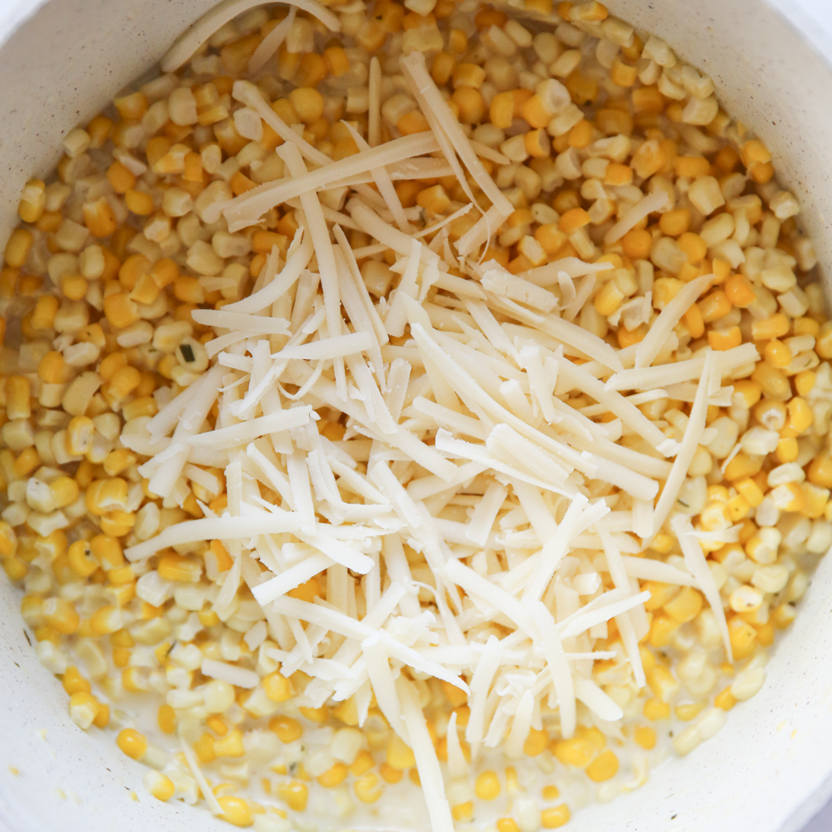pot of corn with creamy sauce and shredded cheese on top