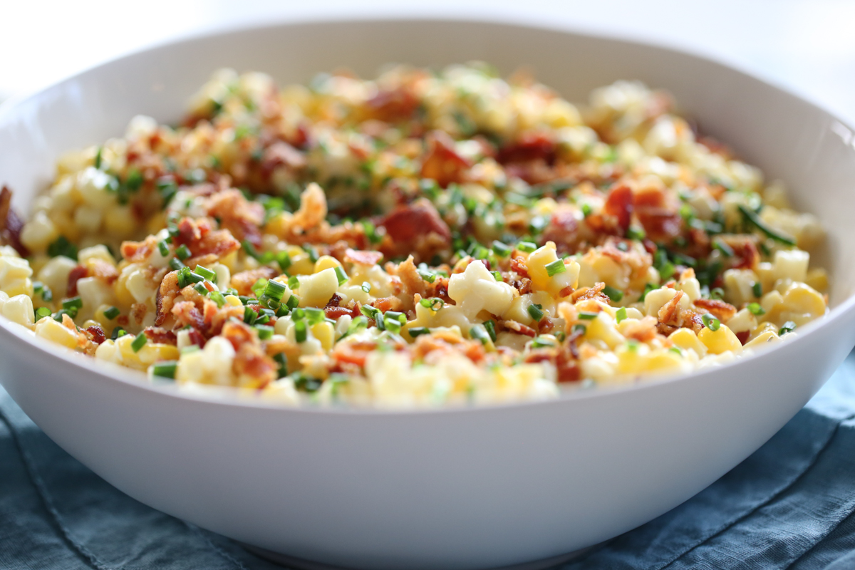 white bowl on a set table with crumbled bacon and chives on top