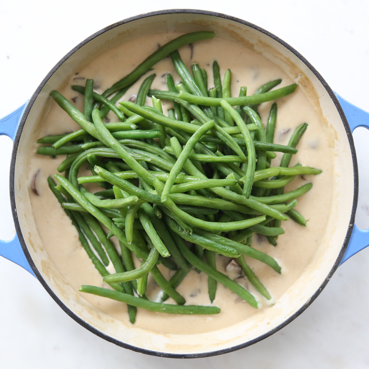 adding fresh green beans into an easy cream sauce