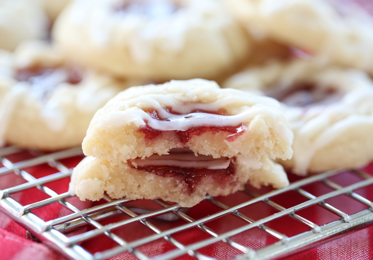 raspberry thumbprint cookies broken in half on a baking rack