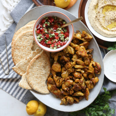 Sheet pan chicken shawarma on a plate with salad and flatbread