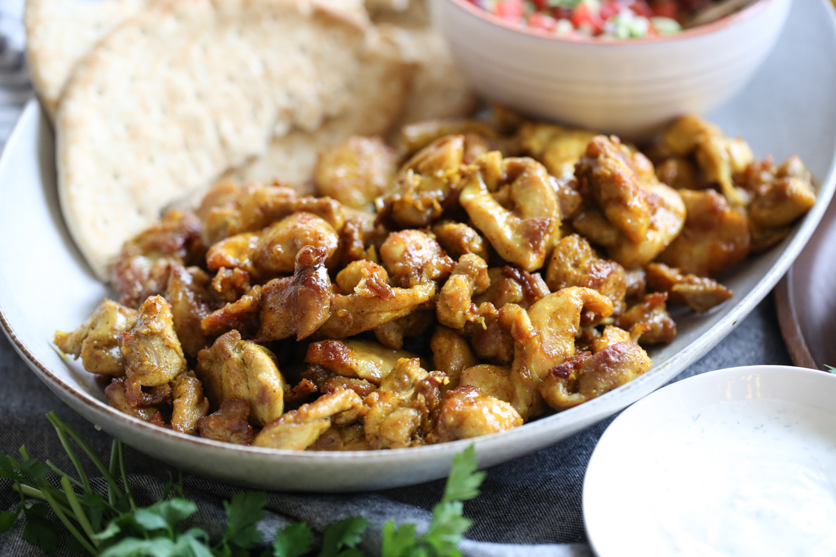 Sheet pan chicken shawarma on a plate with salad and flatbread