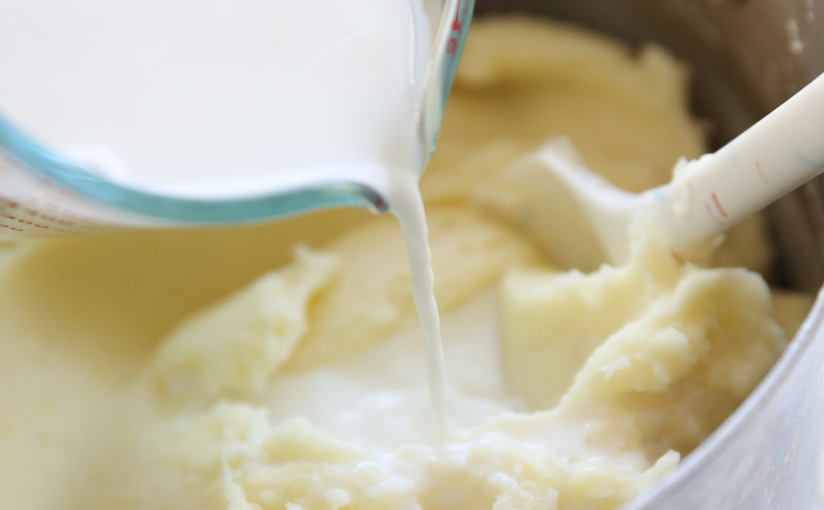 pouring milk into mashed potatoes