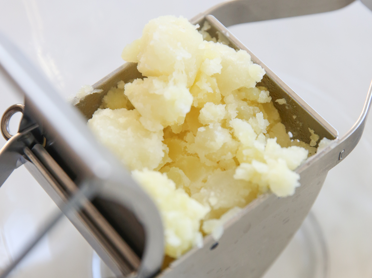 cooked baked potatoes in a potato ricer 