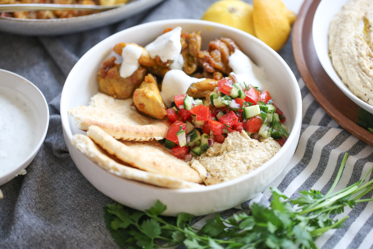 Sheet pan chicken shawarma on a plate with salad and flatbread