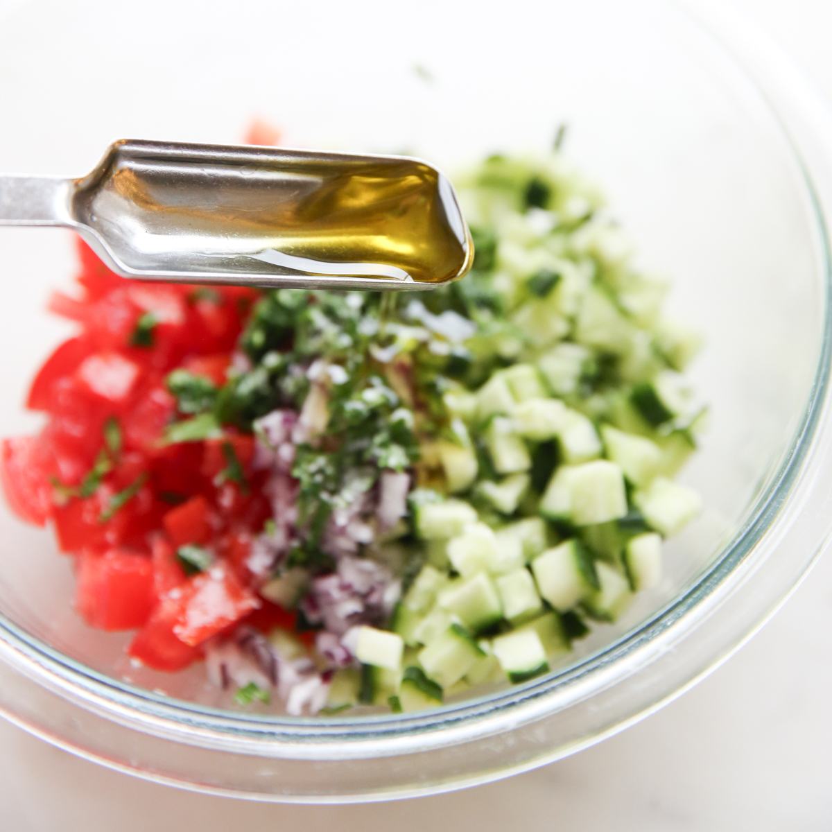 pouring olive oil over tomato salad
