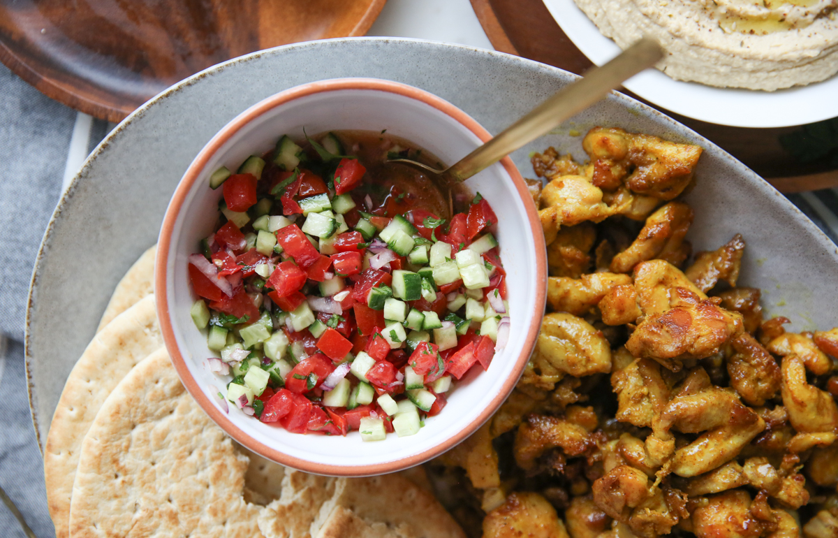 tomato and cucumber salad in a white bowl on a platter