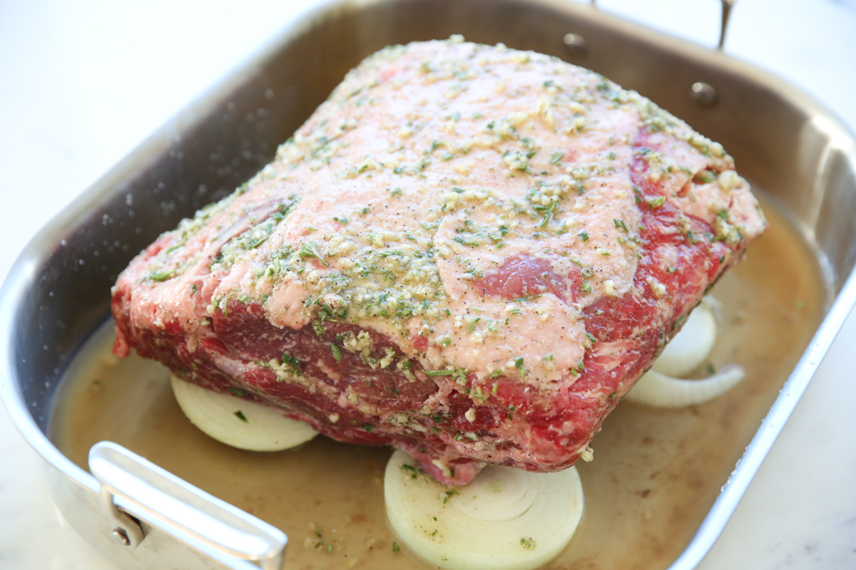 bone-in rib roast sitting on top of onions in a roasting pan