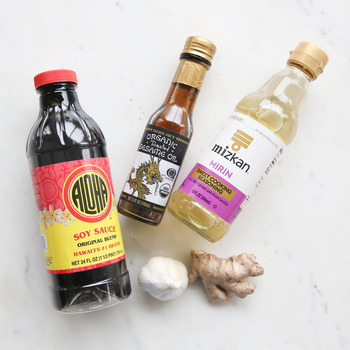 soy sauce, mirin, sesame oil, garlic, and ginger on a counter