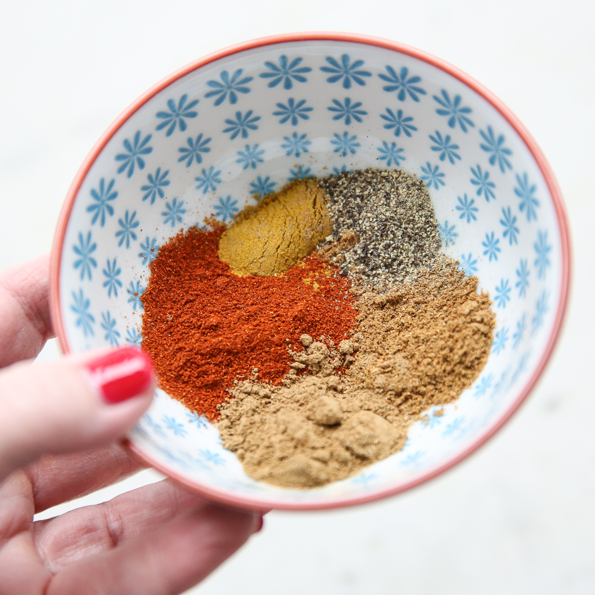 hand holding a blue bowl of spices