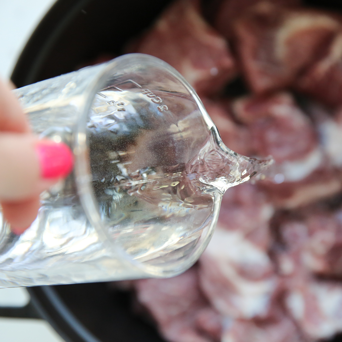 pouring water into a pan of pork