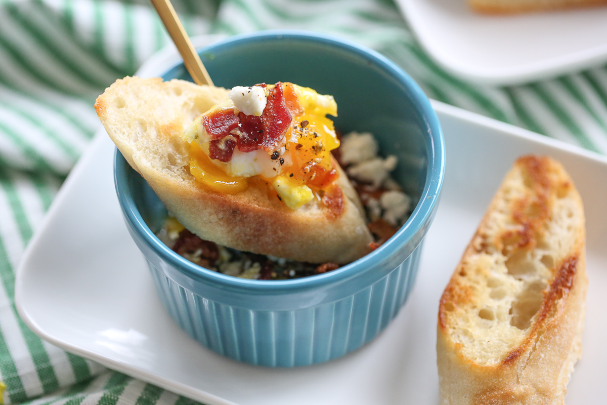 baked eggs in a ramekin with a baguette slice on top