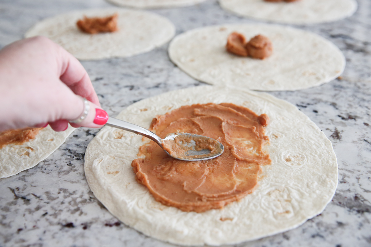 refried beans being spread on tortillas