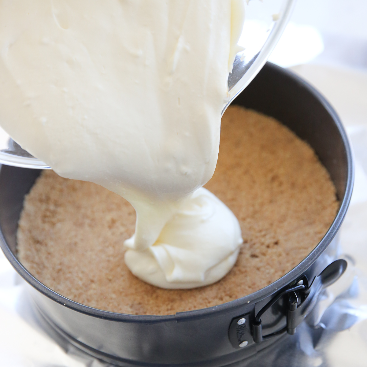 pouring cheesecake batter into springform pan