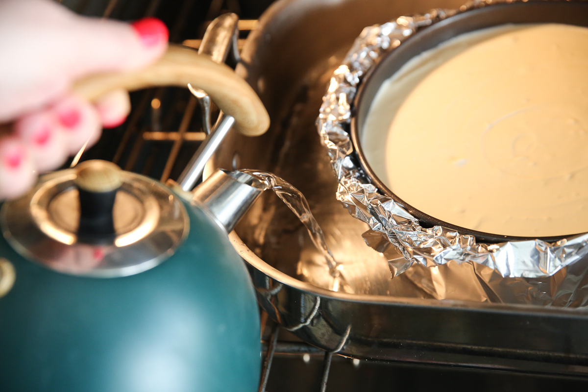 pouring hot water from a kettle into a cheesecake waterbath