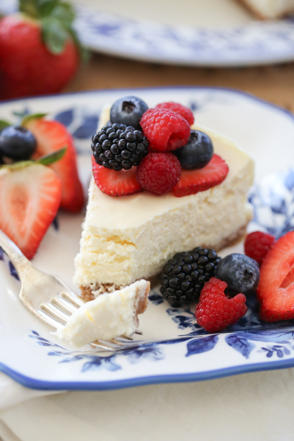slice of cheesecake on a plate with fresh berries and a bite taken out of it