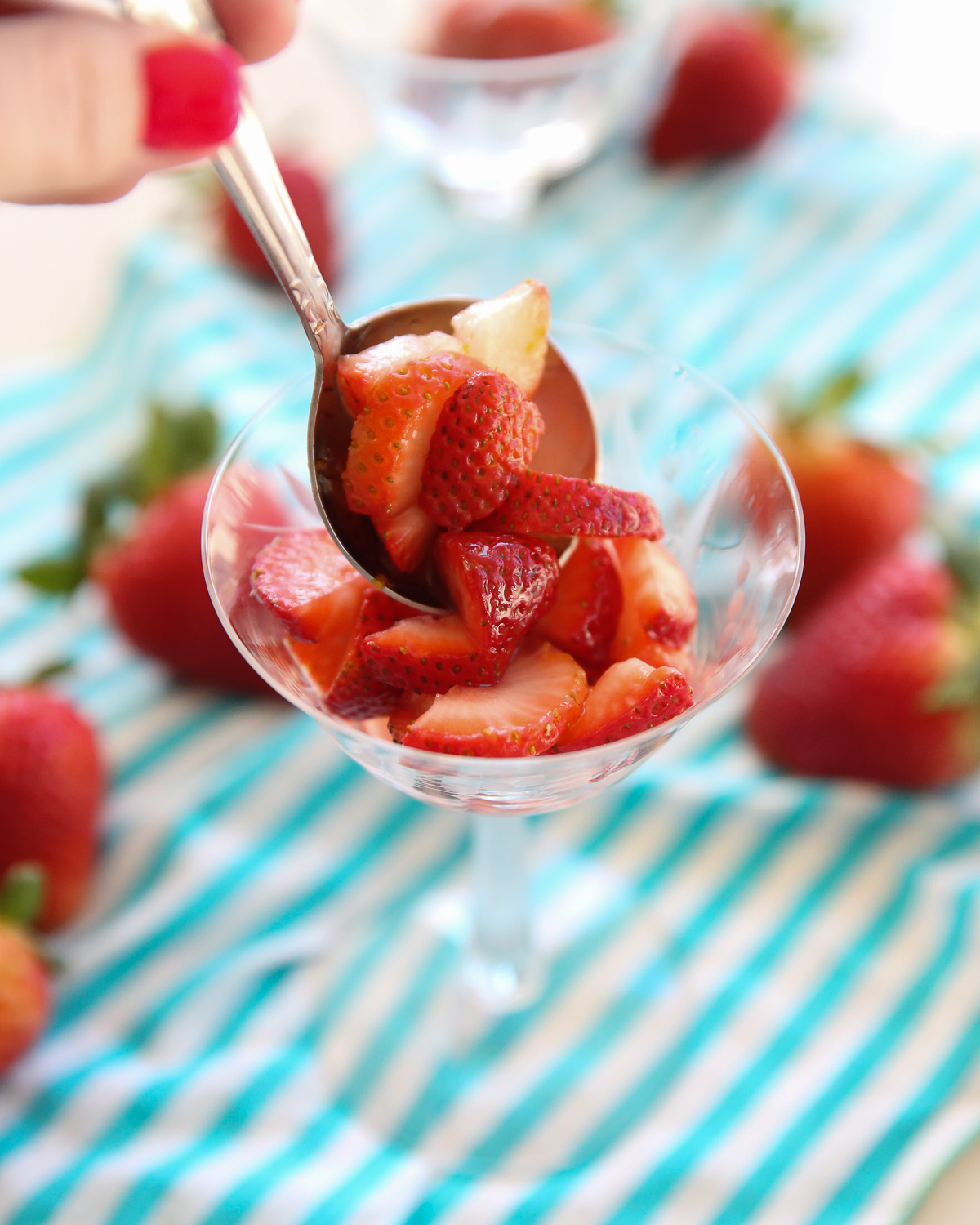spooning strawberries into a crystal glass