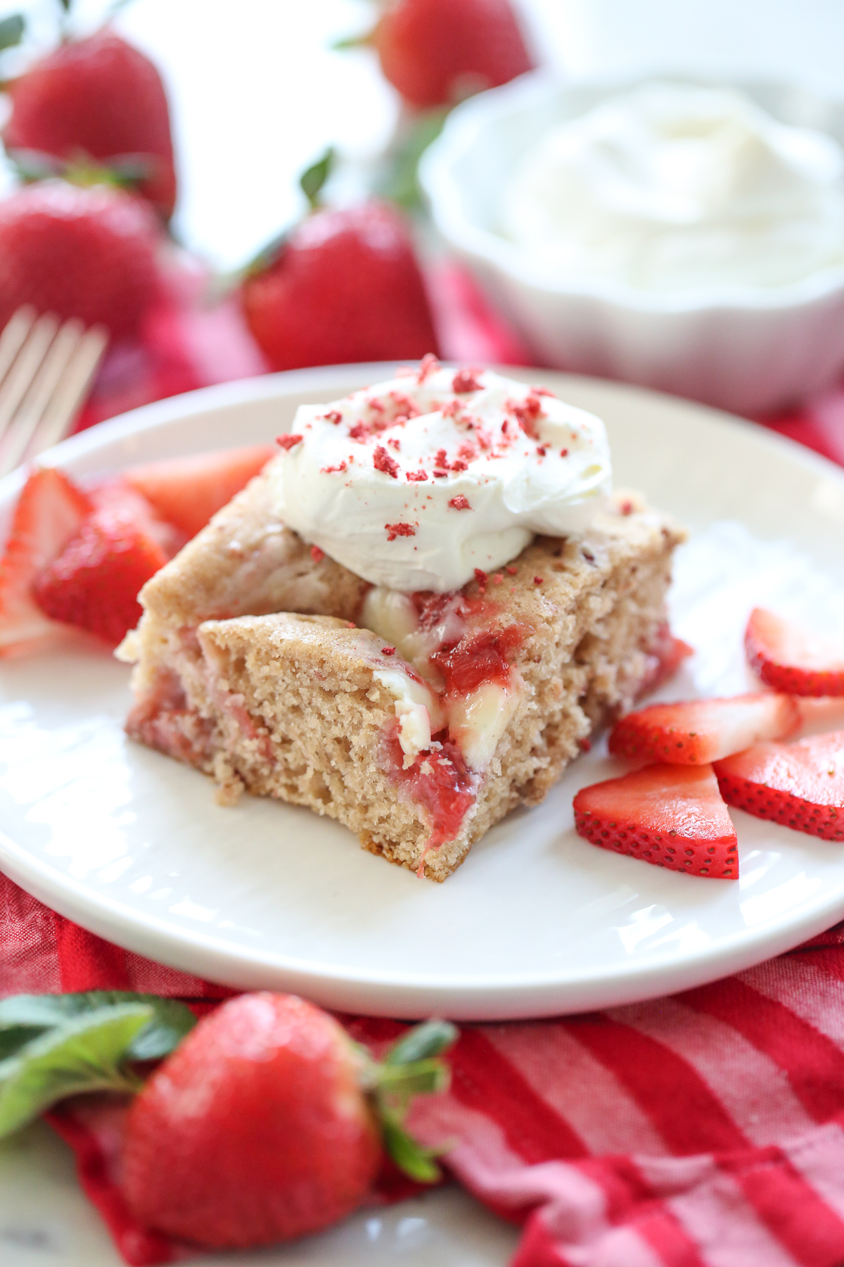 Strawberry Cheesecake Swirl Cake on a white plate with berries and cream
